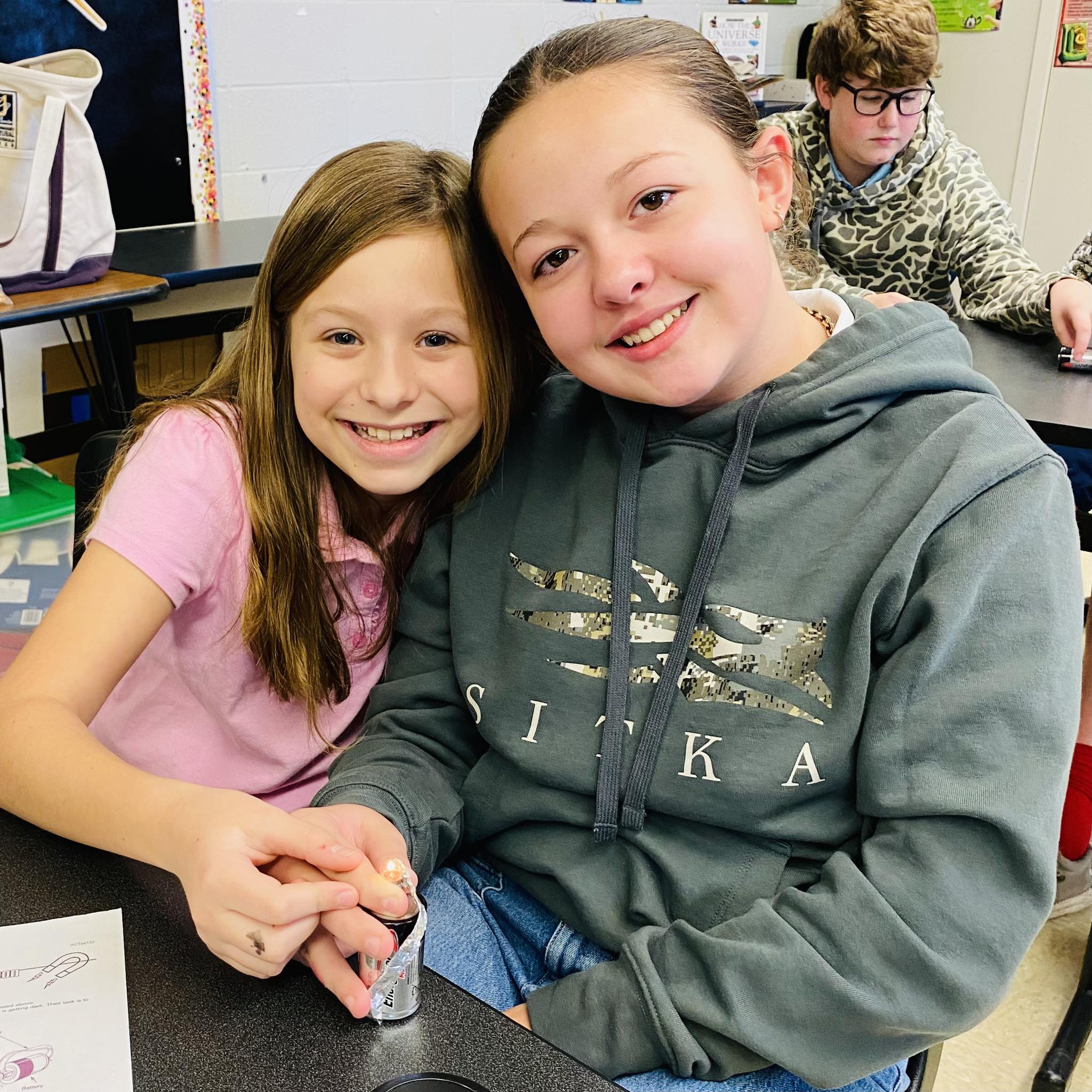 Two girls holding a tiny light.